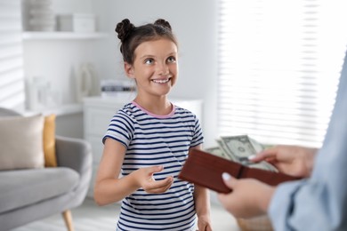 Mother giving pocket money to her daughter at home