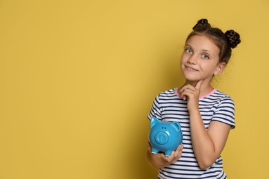 Pocket money. Cute girl with piggy bank on yellow background, space for text