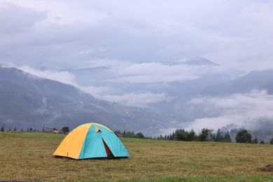 Photo of Tent on green grass in mountains, space for text