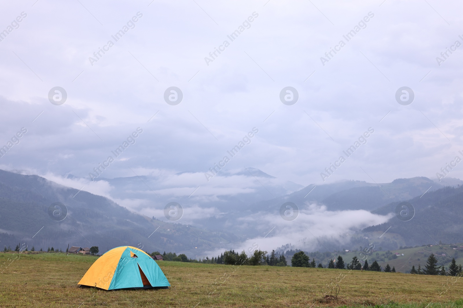 Photo of Tent on green grass in mountains, space for text