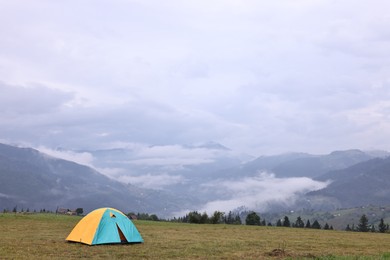 Photo of Tent on green grass in mountains, space for text