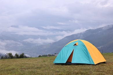 Photo of Tent on green grass in mountains, space for text