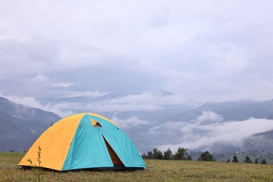 Photo of Tent on green grass in mountains, space for text