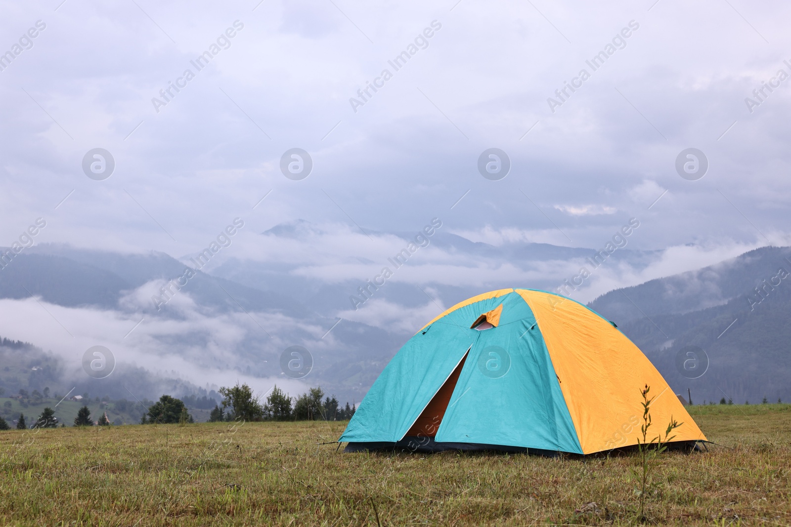 Photo of Tent on green grass in mountains, space for text