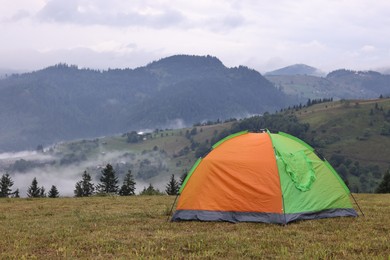 Photo of Tent on green grass in mountains, space for text