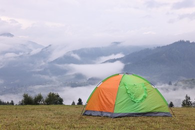 Photo of Tent on green grass in mountains, space for text