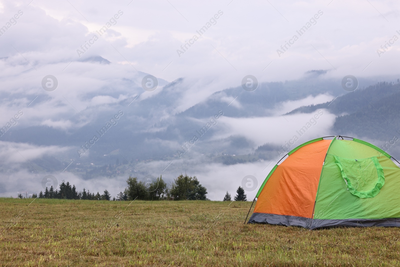 Photo of Tent on green grass in mountains, space for text