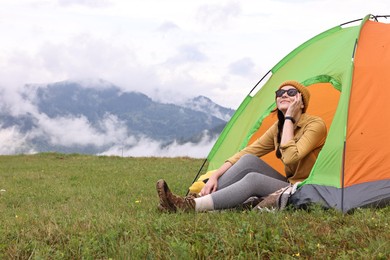 Photo of Young camper and tent in mountains. Active tourism