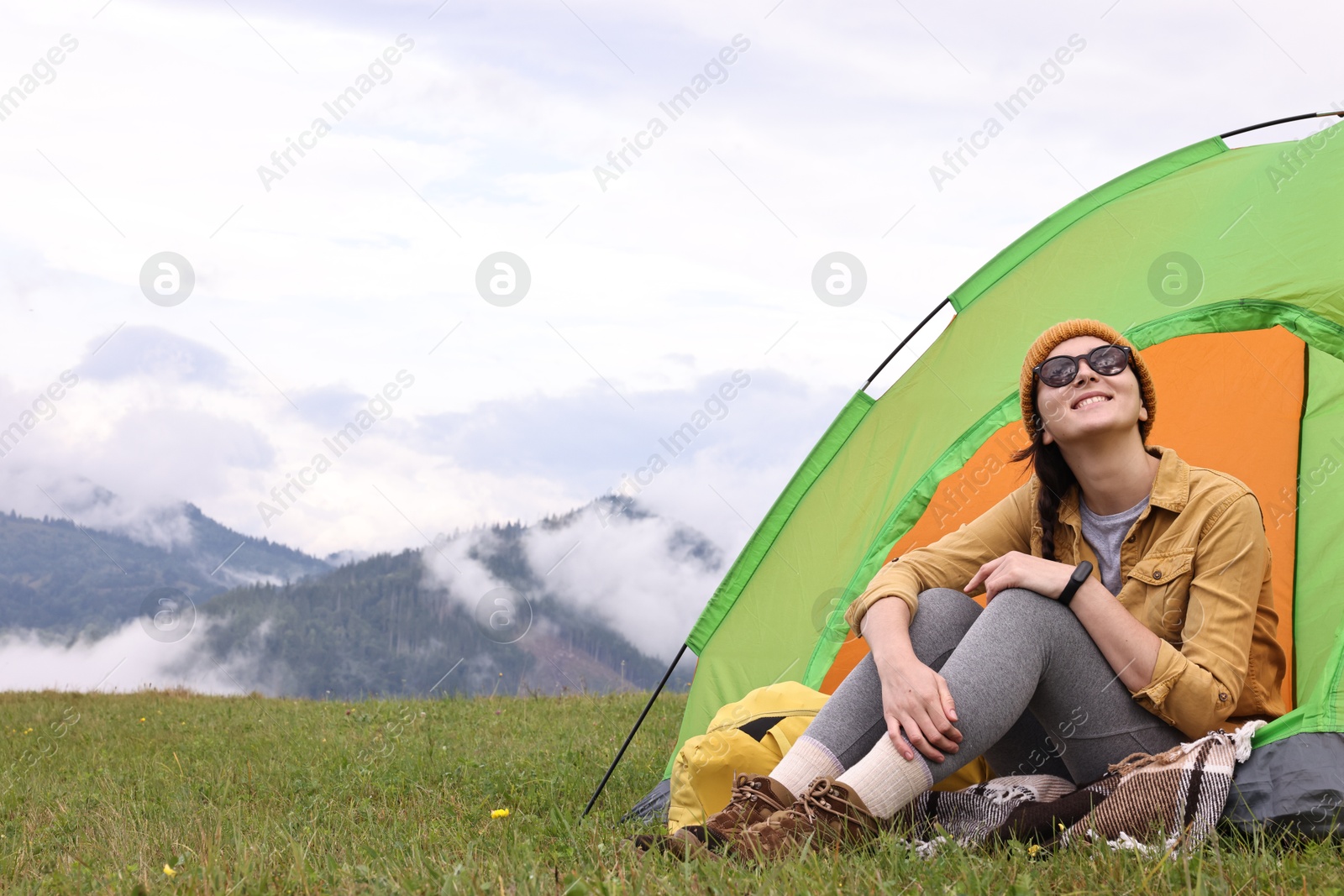 Photo of Young camper and tent in mountains. Active tourism