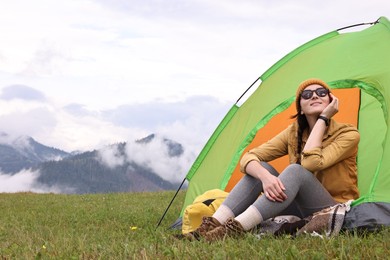 Photo of Young camper and tent in mountains. Active tourism