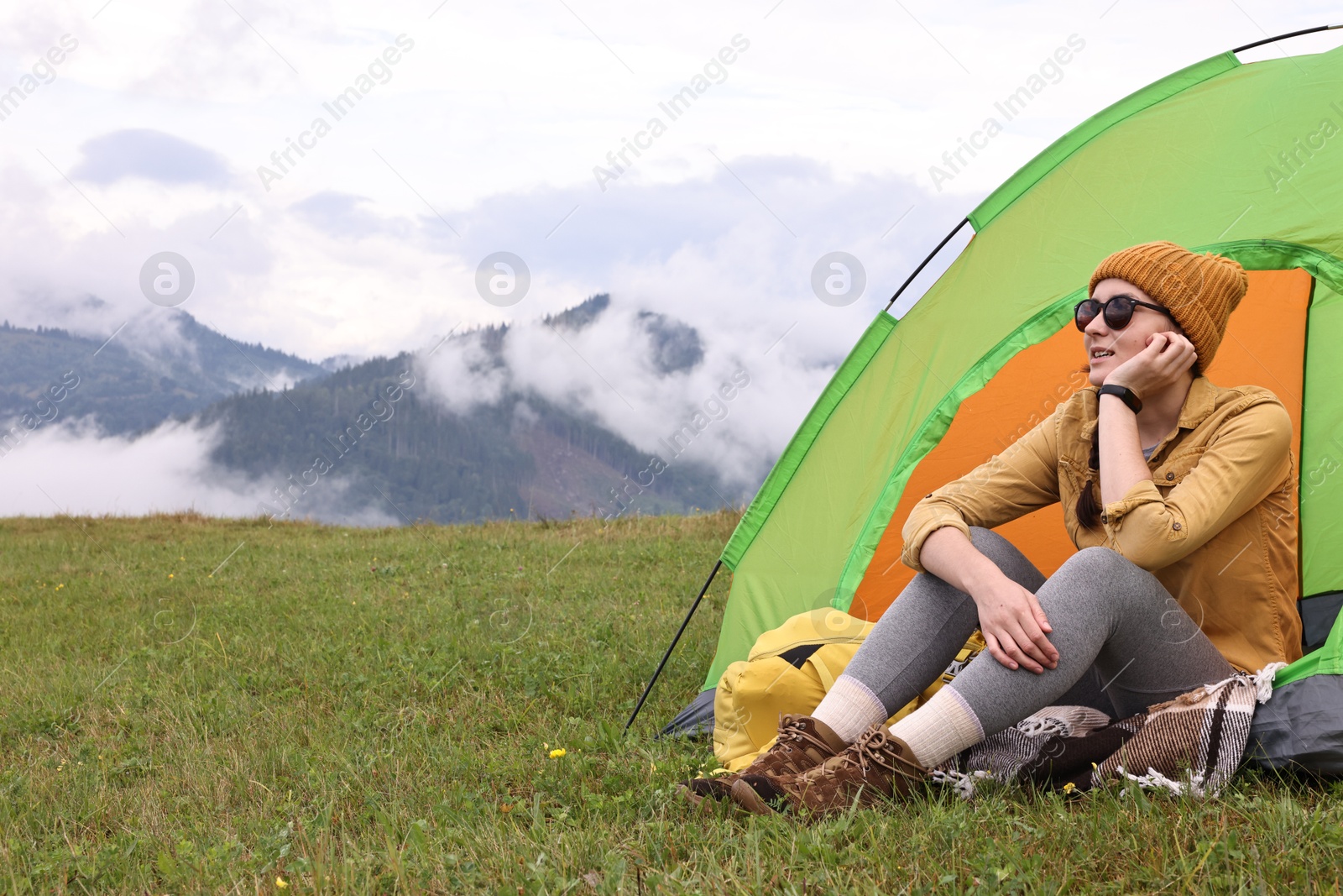 Photo of Young camper and tent in mountains. Active tourism