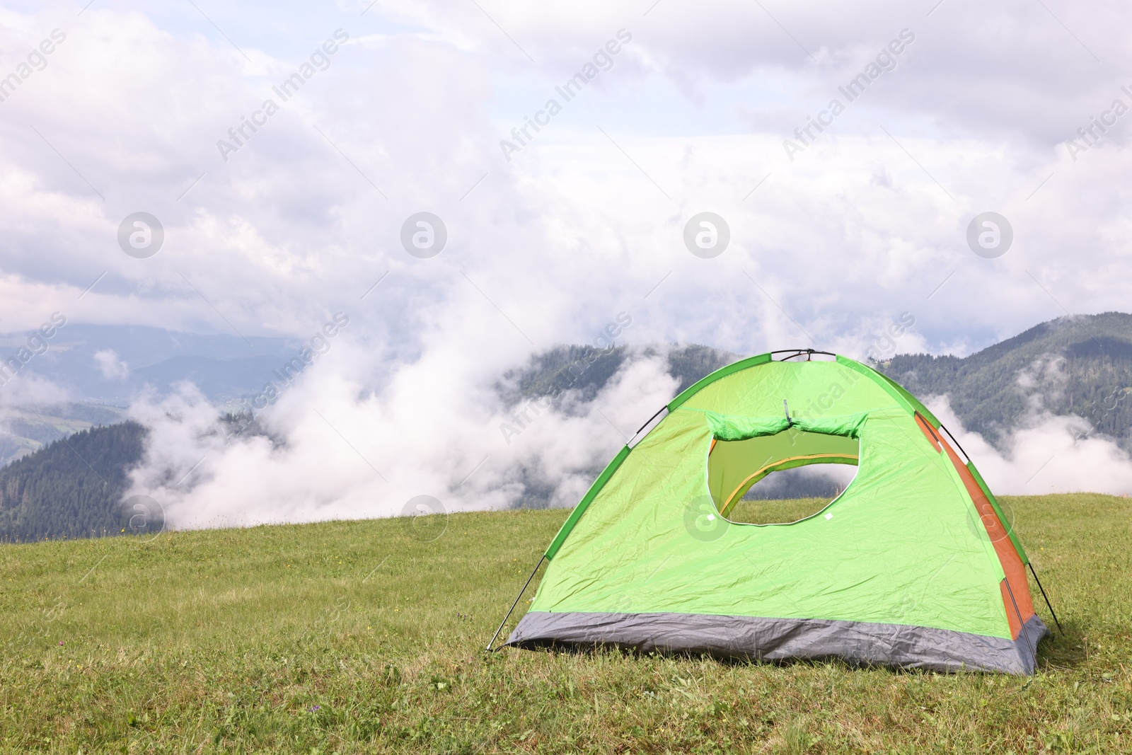 Photo of Tent on green grass in mountains, space for text