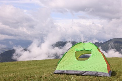 Photo of Tent on green grass in mountains, space for text