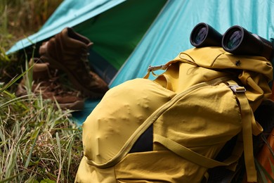 Photo of Tent, backpack, binoculars and shoes on green grass outdoors