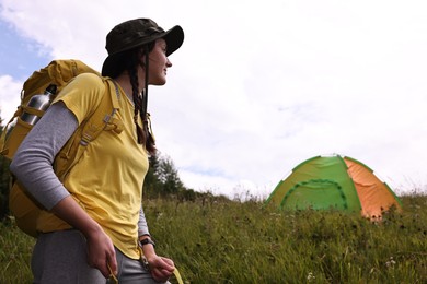 Young camper with backpack and tent in mountains, low angle view. Active tourism