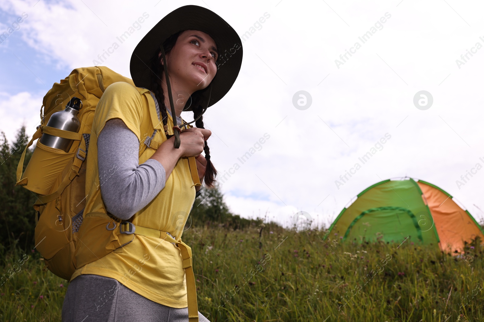 Photo of Young camper with backpack and tent in mountains, low angle view. Active tourism