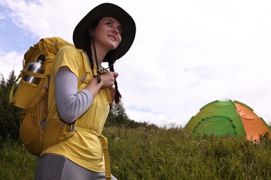 Photo of Young camper with backpack and tent in mountains, low angle view. Active tourism