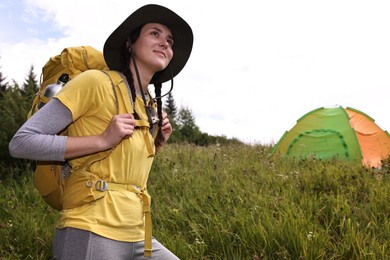 Photo of Young camper with backpack and tent in mountains, low angle view. Active tourism