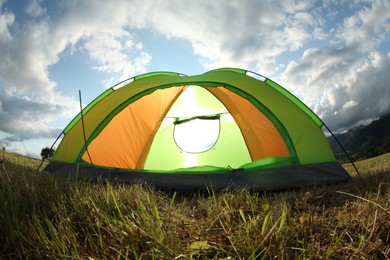 Photo of Tent on green grass in mountains, low angle view. Fisheye lens effect