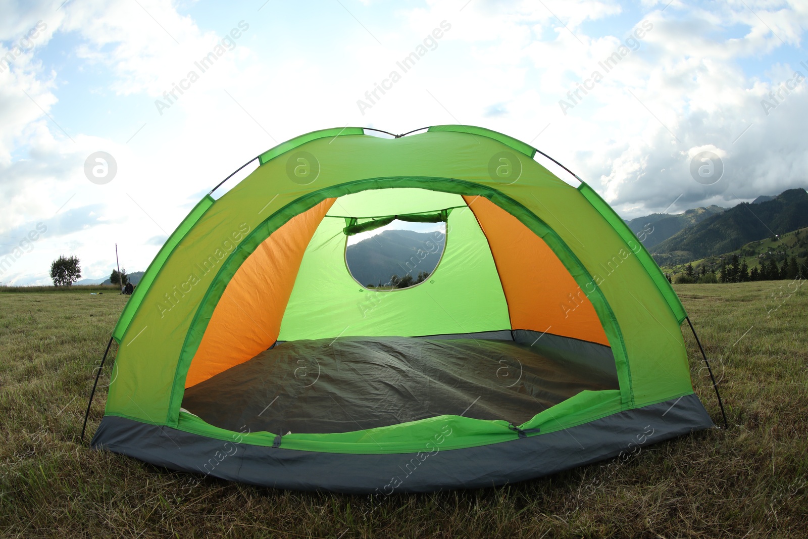 Photo of Tent on green grass in mountains. Camping equipment