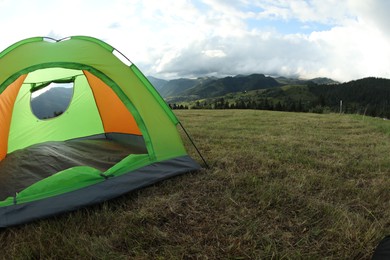 Tent on green grass in mountains, space for text