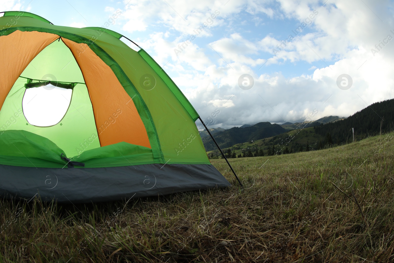 Photo of Tent on green grass in mountains, space for text