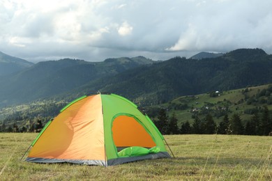 Tent on green grass in mountains, space for text