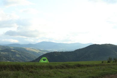 Photo of Tent on green grass in mountains, space for text