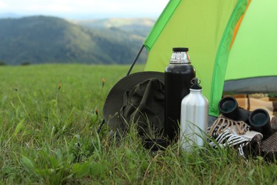 Photo of Tent and camping equipment on green grass in mountains, space for text