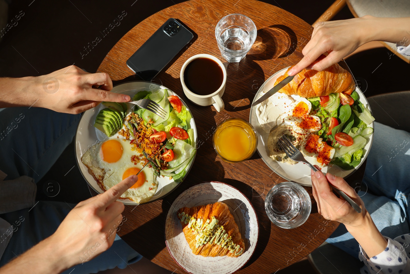 Photo of Couple having tasty breakfast at wooden table in cafe, top view