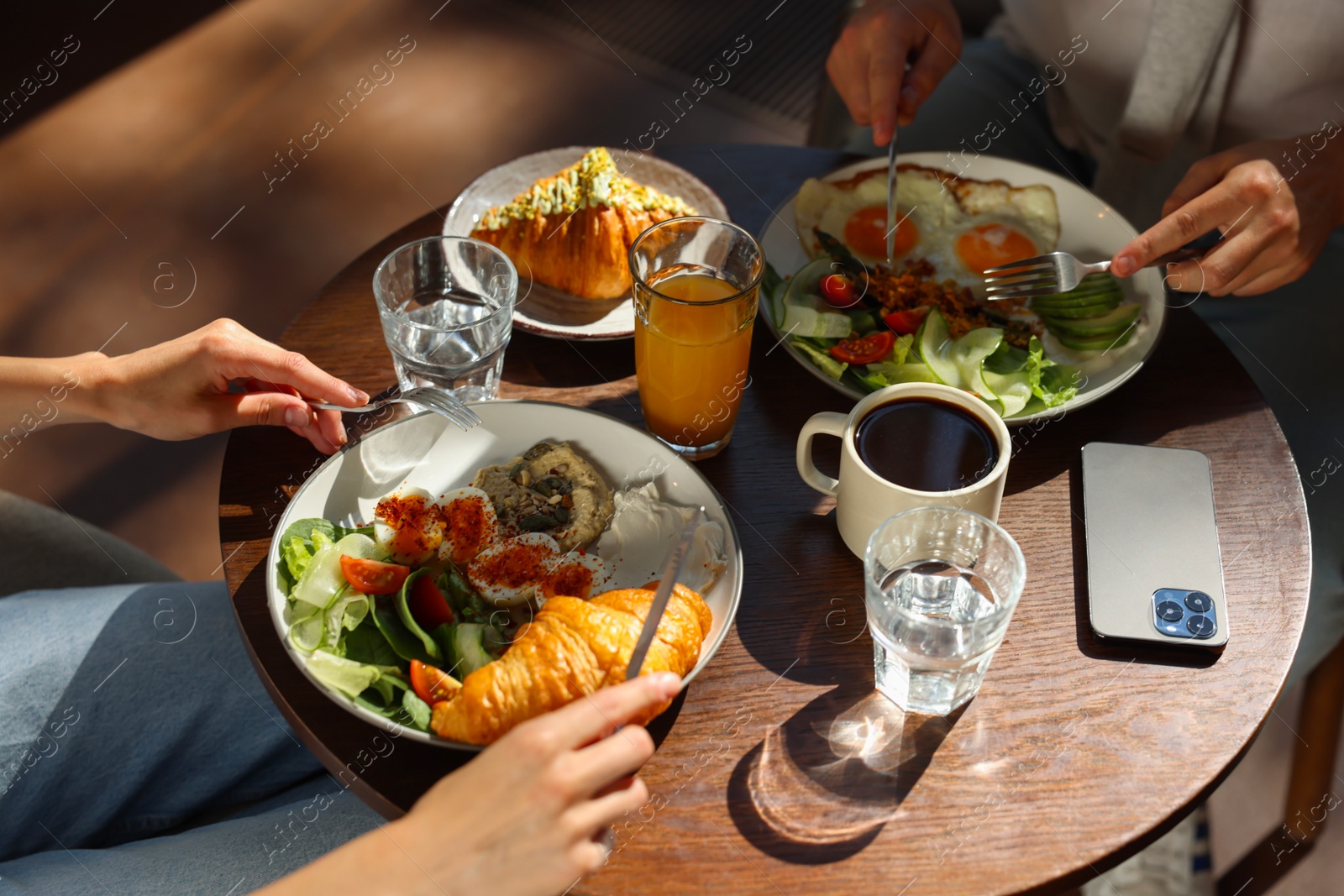 Photo of Couple having tasty breakfast at wooden table in cafe, closeup