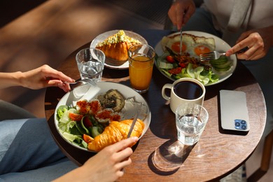 Photo of Couple having tasty breakfast at wooden table in cafe, closeup