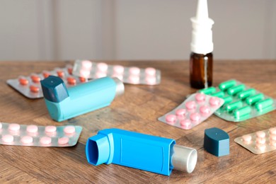 Photo of Different asthma medications on wooden table indoors, closeup