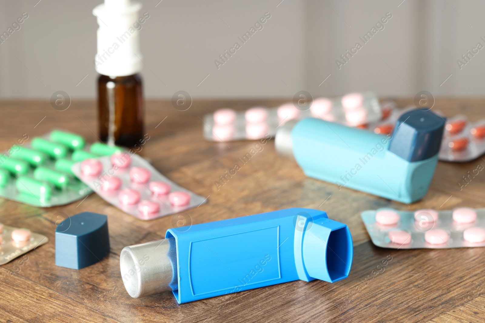 Photo of Different asthma medications on wooden table indoors, closeup