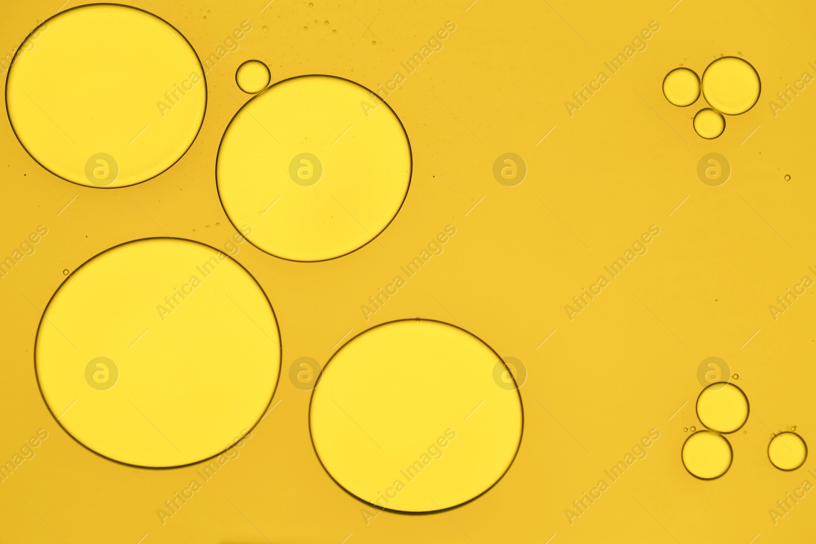 Photo of Sample of cosmetic oil on dark yellow background, macro view