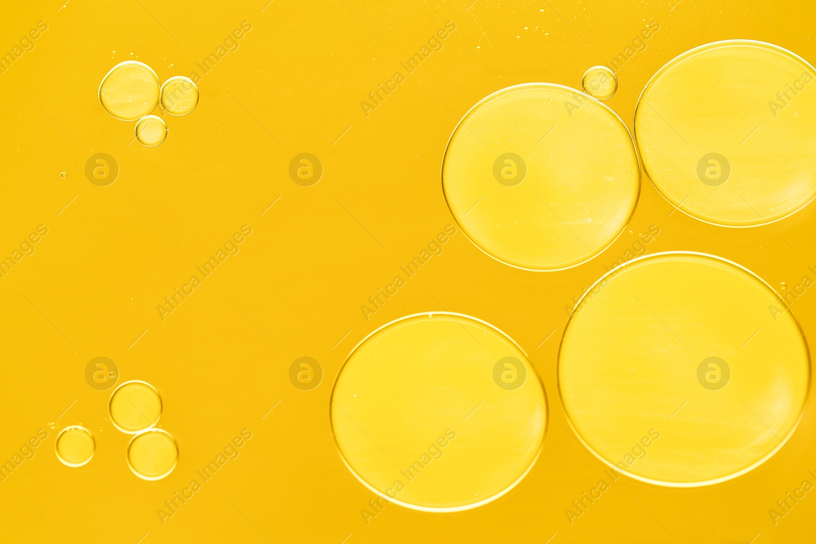 Photo of Sample of cosmetic oil on dark yellow background, macro view