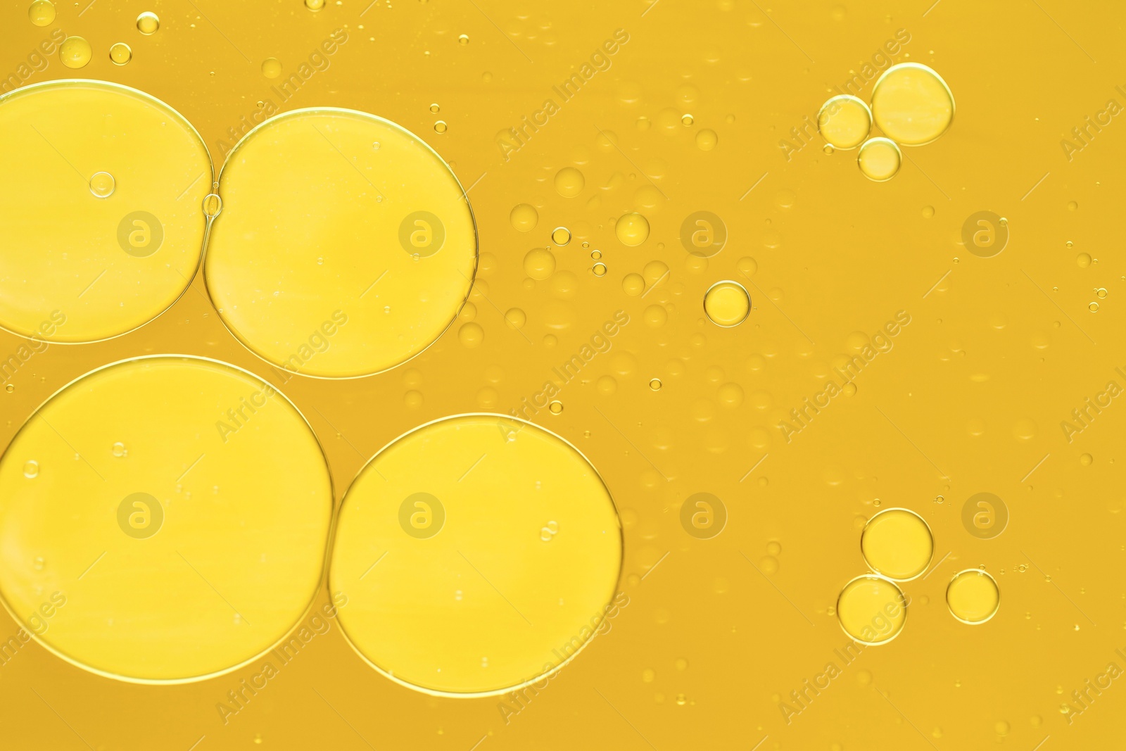 Photo of Sample of cosmetic oil on dark yellow background, macro view