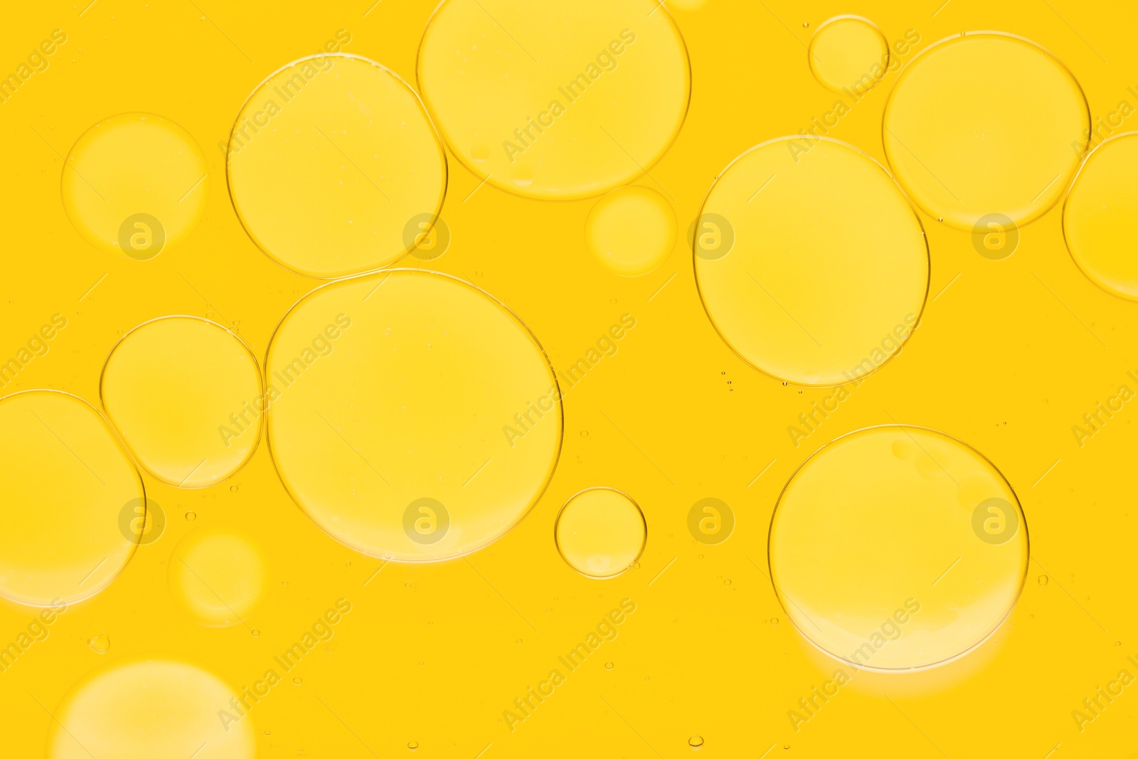 Photo of Sample of cosmetic oil on yellow background, macro view