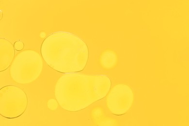 Photo of Sample of cosmetic oil on yellow background, macro view