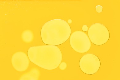 Photo of Sample of cosmetic oil on yellow background, macro view