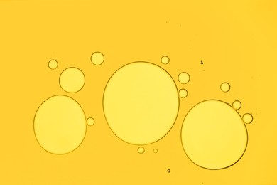 Photo of Sample of cosmetic oil on yellow background, macro view