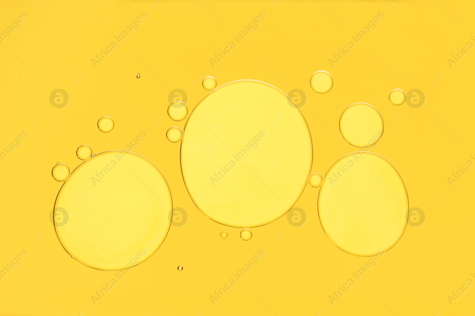 Photo of Sample of cosmetic oil on yellow background, macro view