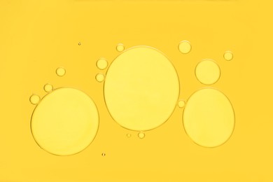 Sample of cosmetic oil on yellow background, macro view