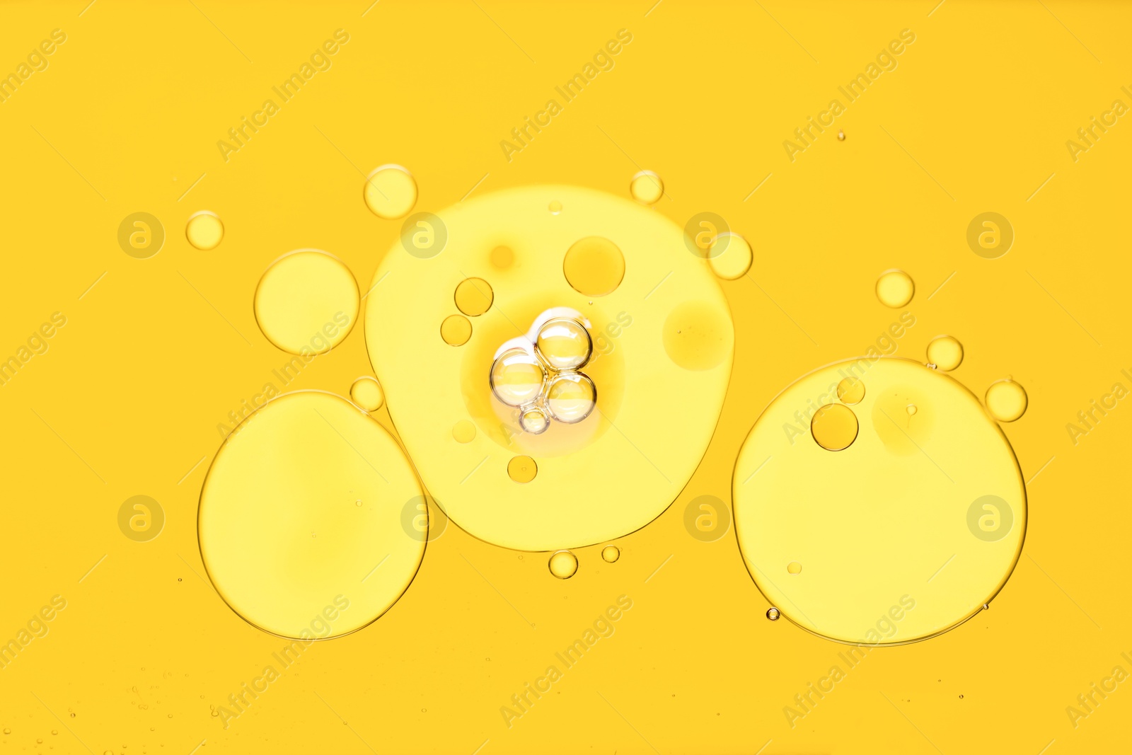 Photo of Sample of cosmetic oil on yellow background, macro view