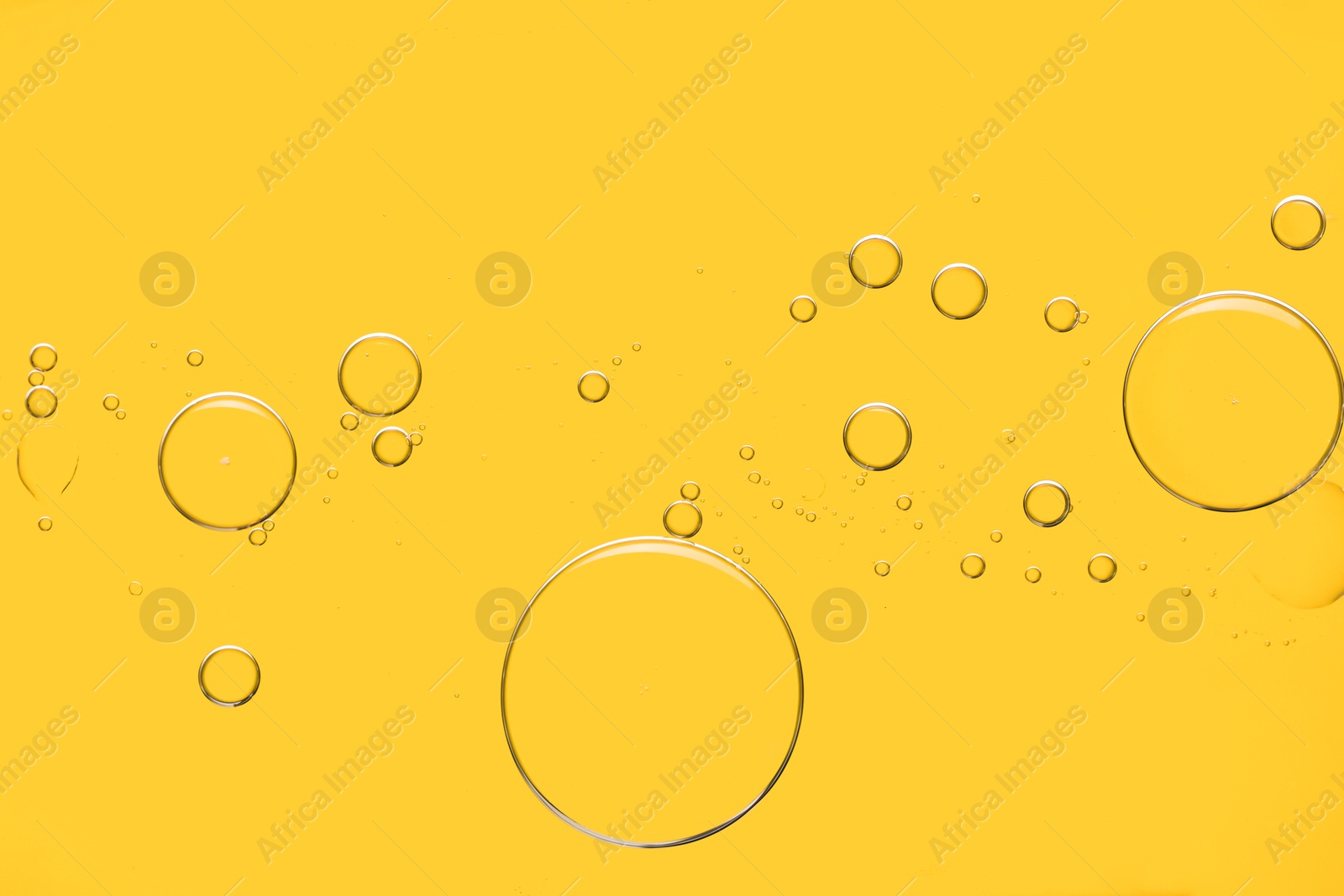 Photo of Sample of cosmetic oil on yellow background, macro view