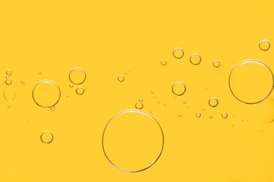 Photo of Sample of cosmetic oil on yellow background, macro view