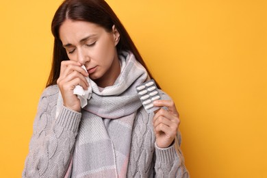 Photo of Sick woman with tissue and pills on orange background. Cold symptoms