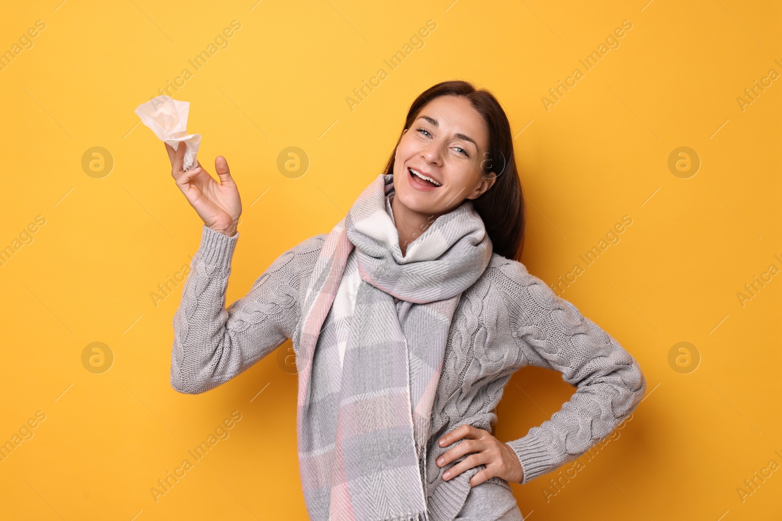 Photo of Smiling woman with tissue on orange background. Cold symptoms