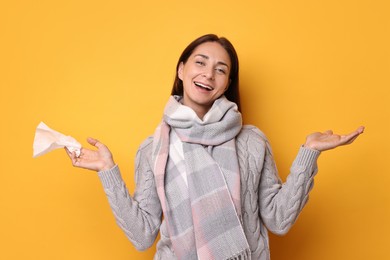 Photo of Smiling woman with tissue on orange background. Cold symptoms