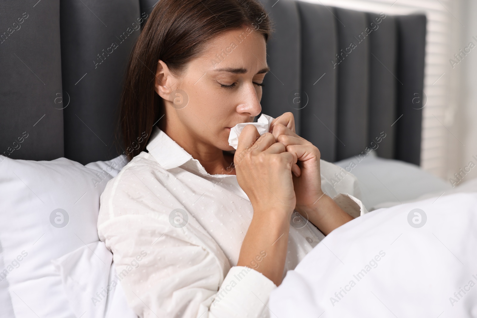 Photo of Sick woman with tissue in bed. Cold symptoms